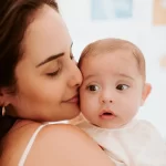 Ensaio fotográfico em casa de mãe com bebê no colo cheirando o rosto do bebê em Ilhéus-BA